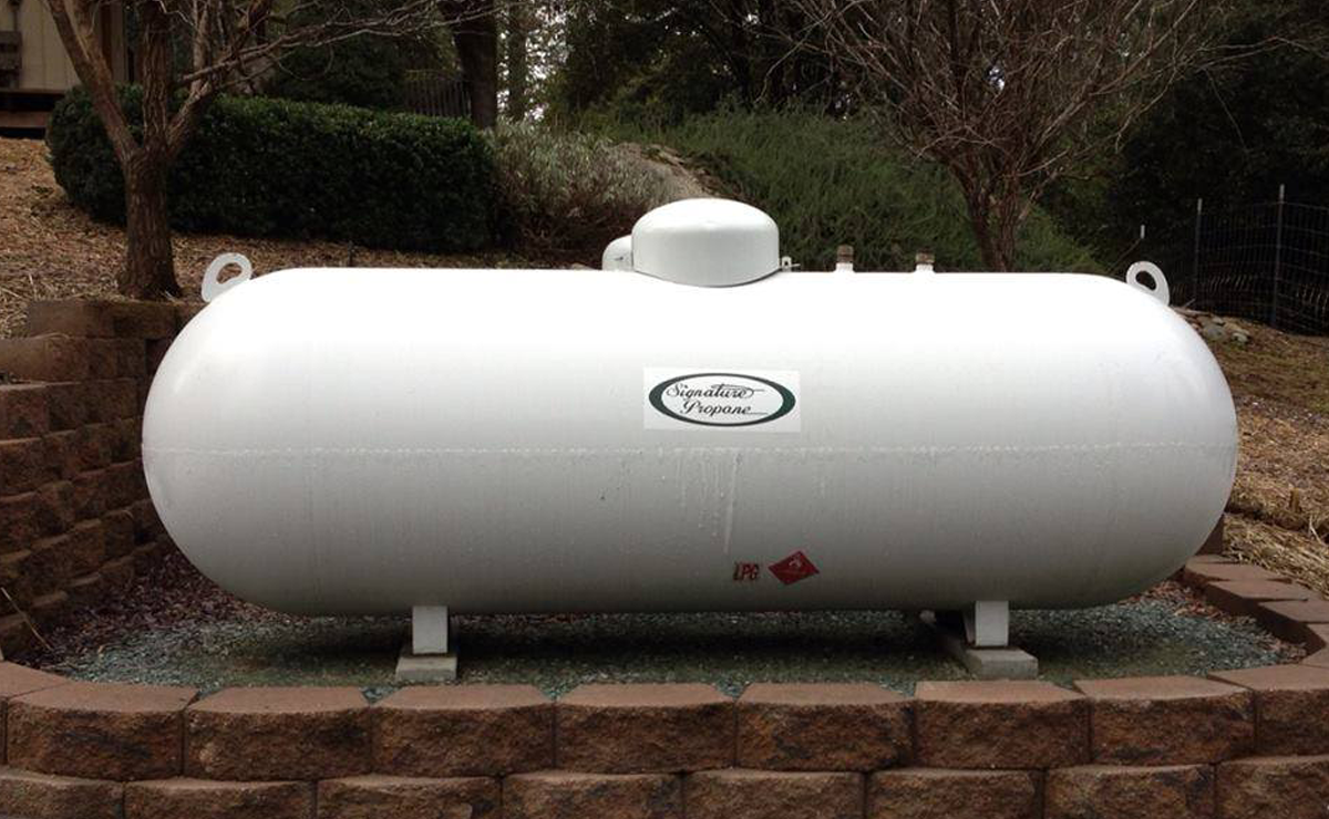 In the garden is a propane tank, on a concrete slab. 